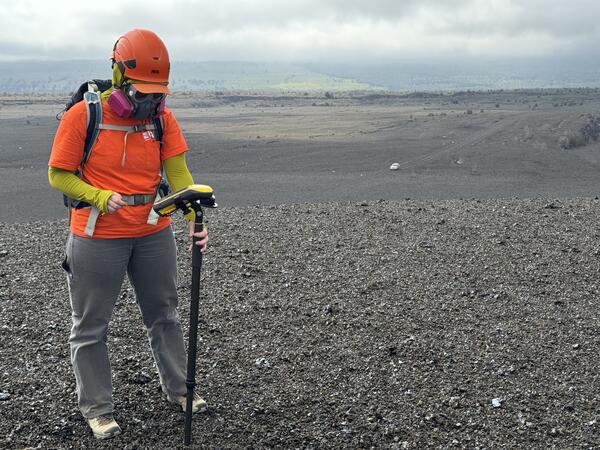 Color photograph of a scientist measuring a new volcanic deposit