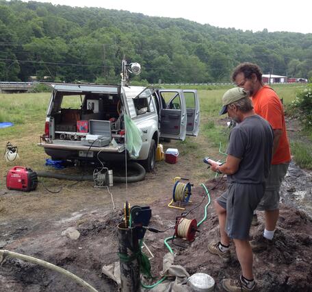 2 men setting up geophysical logging at a borehole well in a field in western MD