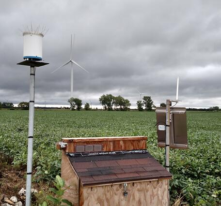 Equipment enclosure and rain gage by agricultural field in Michigan