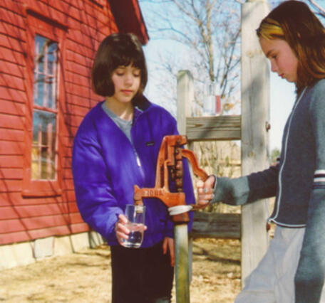 Girls getting a glass of water at a well pump at The Tollgate House, Meridian Historical Village, Okemos, MI 